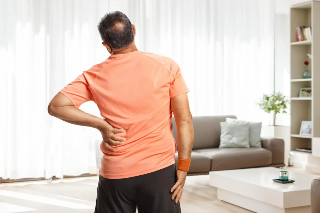Person holding their lower back while experiencing back pain Person holding their lower back while experiencing back pain